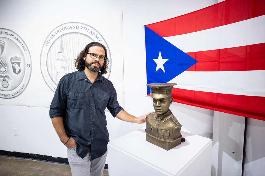 Carlos standing next to a bust of his grandfather