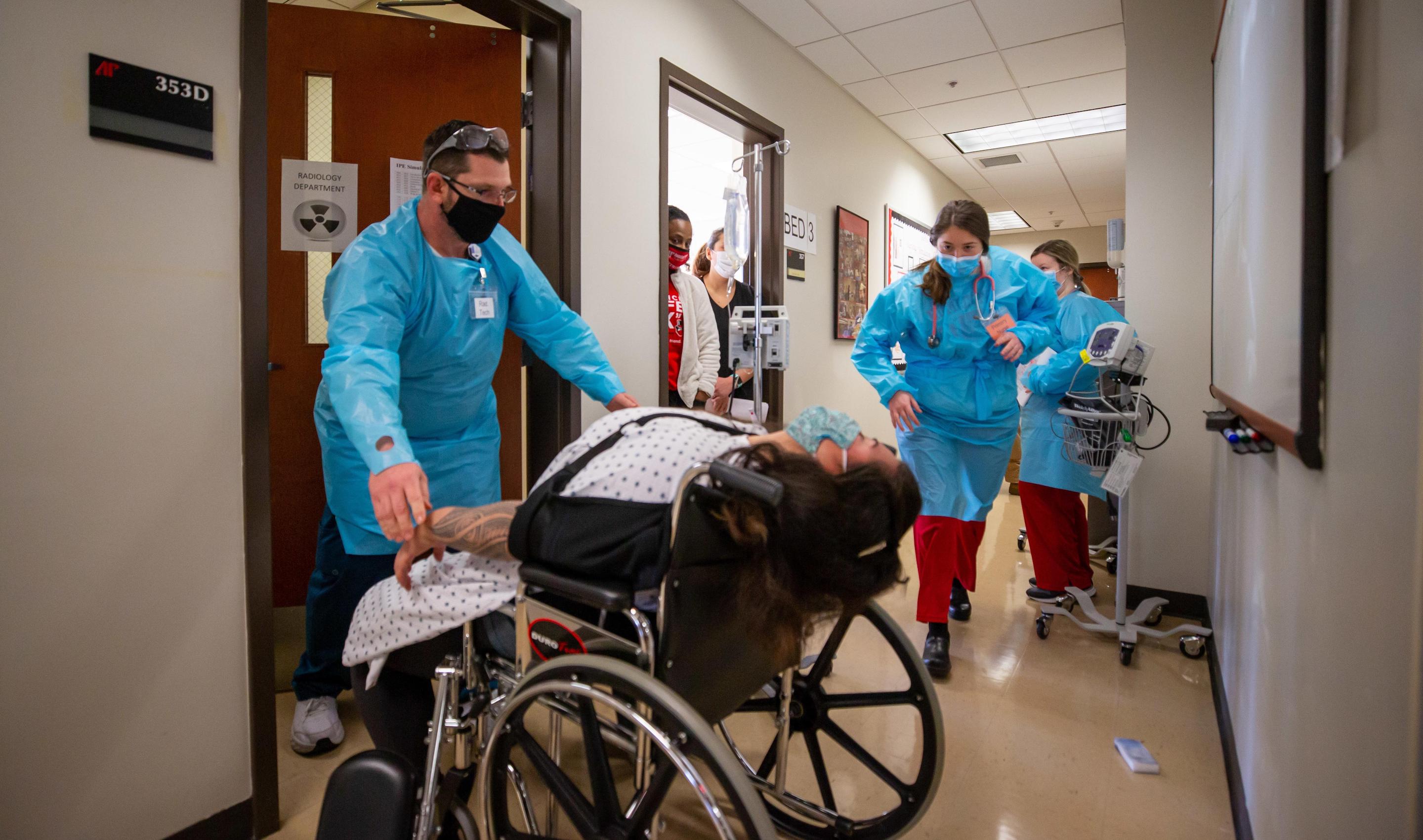 Earlier this month, about 70 Austin Peay State University nursing and radiologic technology students navigated a two-day interdisciplinary simulation where they learned the real-life stakes of collaboration and communication.  The exercise was the first of its kind at Austin Peay, an APSU School of Nursing simulation that brought students from another college – the College of Science, Technology, Engineering and Mathematics – to the school’s simulation lab.  APSU Nursing Simulation Center’s Adrienne Wilk explained the high stakes exercise to the senior-level students before they stepped into the lab.  “Today is for us to improve patient safety and patient outcomes,” she said. “We want you to apply that discipline-specific theoretical knowledge that we’ve lectured to you over the last several months. We want you to apply that knowledge in a real-life clinical setting.”  The objectives of the simulation included understanding the roles each discipline has in a medical setting while collaborating and communicating effectively to improve patient outcomes.  “You have to learn how to communicate,” said Jennifer Thompson, program director for radiography at Austin Peay. “That is one of the biggest takeaways from these scenarios is the students realizing, ‘I had no idea how to talk to the nurses.’  “We need to know how to ask how to help the nurse, and the nurse needs to know how to ask what they can do for you so that you become a healthcare team, not just a rad tech and a nurse,” Thompson added.  Faculty have planned a second interdisciplinary simulation for about 80 junior-level nursing and rad tech students in early April.  Students navigate COVID-19, seizure during simulation  The students separated into teams of two or three nursing students and a rad tech student then rotated among four stations covering two scenarios.  During the March 3-4 exercise, the students cared for a COVID-19 patient and a patient who had fallen and injured her shoulder during a seizure.  Each scenario mimicked real-life settings and included full patient charts and physician orders. Both patients, for example, had doctor’s orders for medical imaging.  In both scenarios, the nursing and rad tech students had to navigate each discipline’s roles while communicating clearly.  The students, for example, had to prepare the COVID-19 patient – played by a high-tech manikin with vital signs – for his diagnostic imaging. The students had to figure out how to position the manikin while keeping him comfortable and the health monitoring equipment secured and working.  A fellow rad tech student volunteered to play the patient in the other scenario and surprised the students with a seizure during medical imaging.  The students gathered with their instructors after each scenario to discuss where they succeeded and where they could improve.  “That’s where all the learning happens,” Wilk said, “especially for visual learners to see the whole patient scenario laid out.”  Thompson agreed: “You don’t realize how much is happening during the simulation until you watch the debriefing.”  ‘We need them to help with the patient’  Nursing senior Daketra Mason’s biggest takeaway centered on communication, especially between disciplines across campus. The School of Nursing is in the College of Behavioral and Health Sciences, and the rad tech program is in CoSTEM’s Department of Allied Health Sciences.  “Throughout the whole sim, I saw how important it is communicating with everybody, with other healthcare workers and the patient,” she said.  Rad tech senior Valerie Picataggio joined Mason and nursing senior Hannah McElroy in the scenario.  “In a real setting, (Valerie) wouldn’t have known what we knew about the patient so we would have had to explain to her what was happening,” Mason said.  The COVID-19 patient in the simulation, for example, had a pressure sore that restricted his movement.  “And from my perspective, I’m used to getting in and getting out, but I could put that patient’s safety at risk because I didn’t know about his pressure sore,” Picataggio said. “For the most part, we stay out of the nurses’ way, get the image and then leave.”  McElroy said the simulation allowed her to recognize the need to collaborate.  “We do work pretty closely with (rad tech),” she said. “They don’t need to stay out of the way, they’re not in the way, we need them to help with the patient as well.”  Picataggio also noted the importance of including a COVID-19 patient in the scenario.  “You don’t treat COVID patients differently just because they’re vented,” she said. “As long as we’re protecting ourselves and being smart, they shouldn’t feel any kind of aversion to them.  “That could be my family member lying there.”  To learn more  • For more about the Department of Allied Health Sciences, visit www.apsu.edu/allied-health/. • For more about the School of Nursing, go to www.apsu.edu/nursing/.