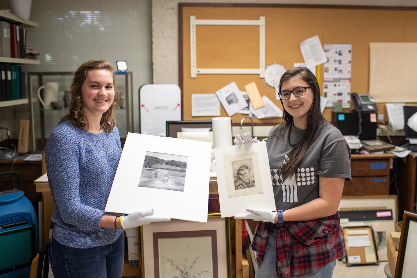 Art students Sarah Potter and Katherine Tolleson hold their discoveries. Potter is holding a Philippe Halsman photo print of Winston Churchill, and Tolleson is holding a drypoint by Alphonse Legros.