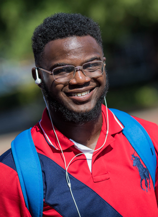 portrait shot of a student with their backpack outside on a sunny day.