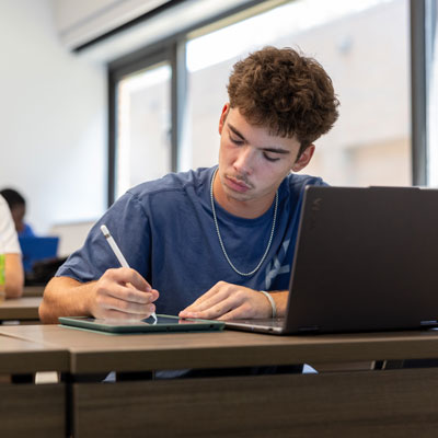 Student sitting in a classroom and working on their ipad.