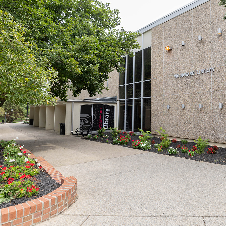 The library building with red and white flowers planted in the garden beds.