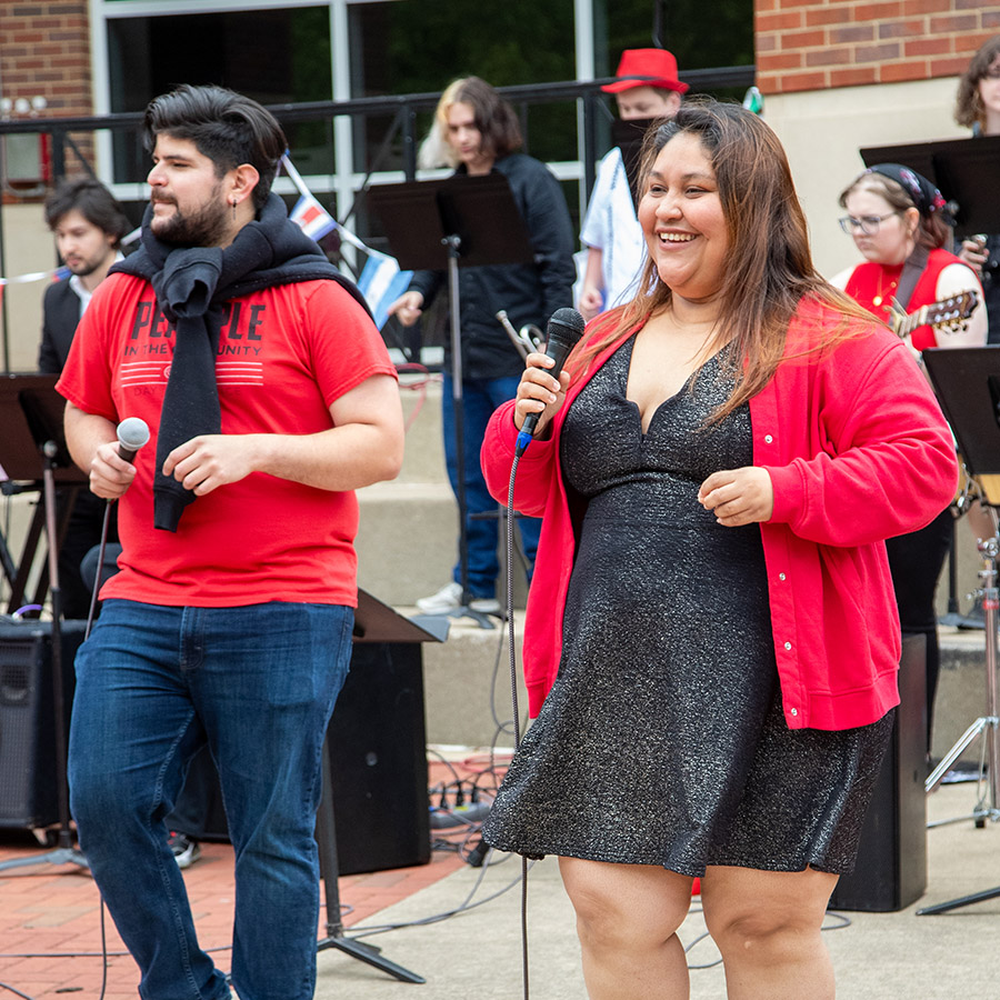 The Sin Fronteras ensemble singers and band performing for a crowd outdoors.