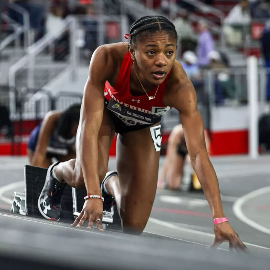 Female track runner poised to take off.