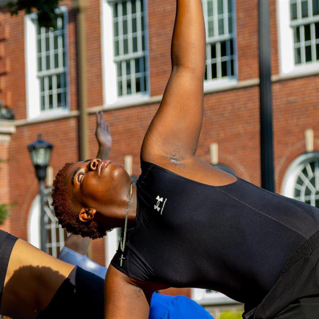 Students doing yoga poses outside on campus.