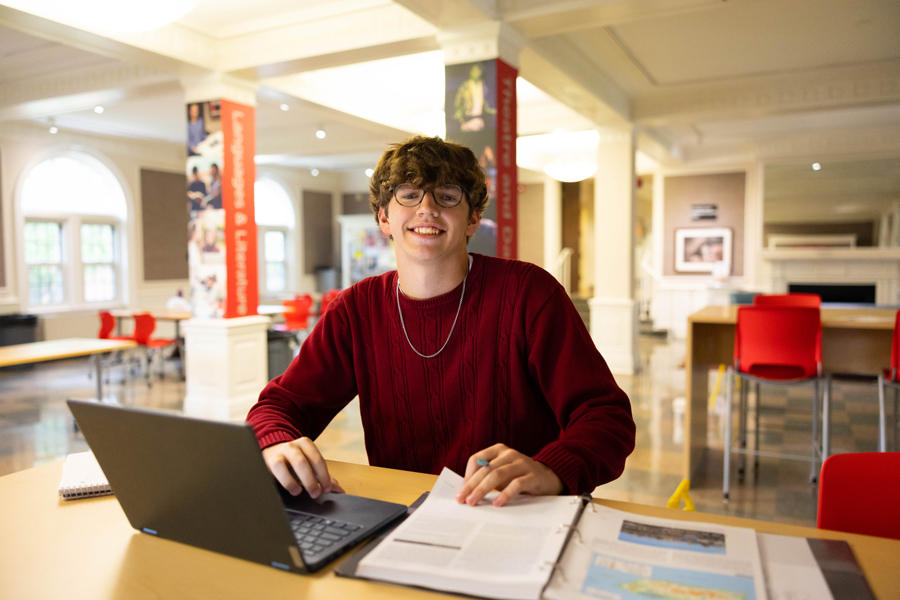 student in the Harned Building with their laptop and notes