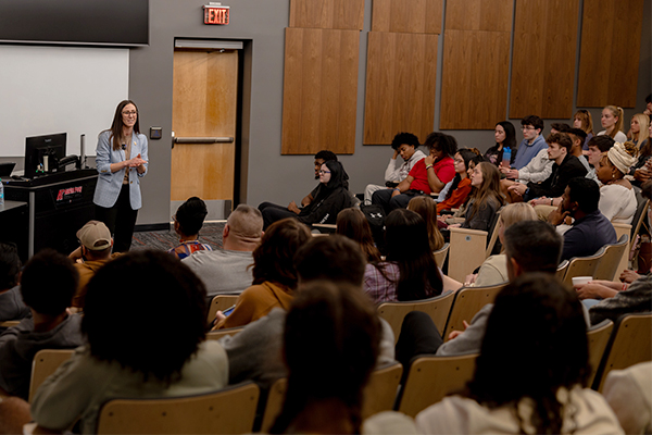 A large group of students sitting in a lecture hall listenign to a visiting speaker.