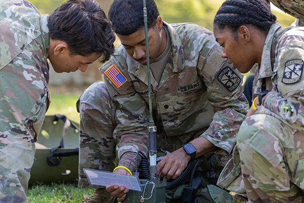 A group of ROTC students in uniform working together on a project.