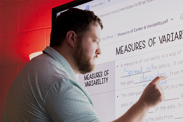 A teaching student during his residency, filling in a worksheet on a digital screen while teaching a class.