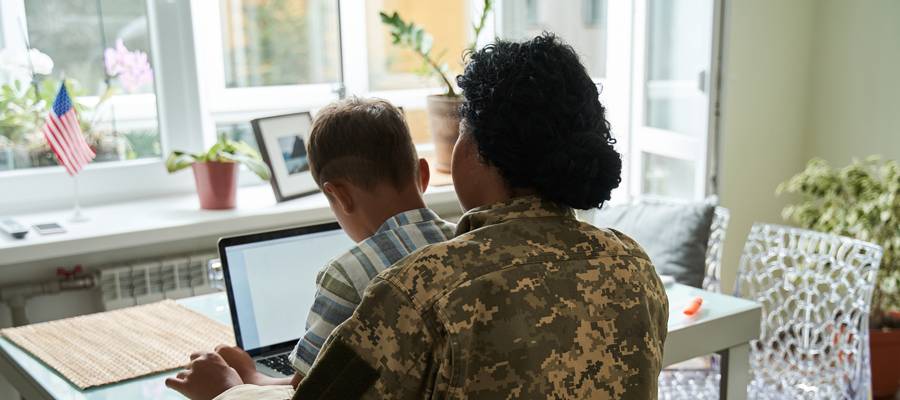 Military Mother and son sitting at kitchen table infront of laptop