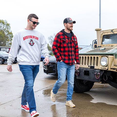 Students walking through a parking lot with a military hummer and BMW vehicles.