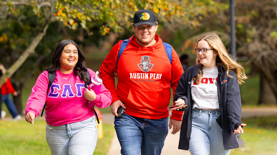 A group of three students walking and talking on campus.