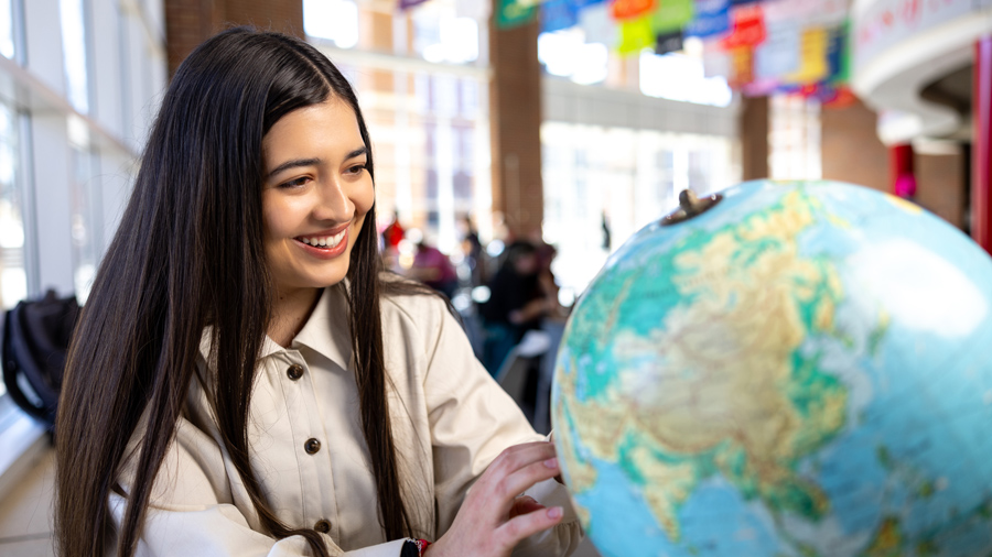 Student looking at a world globe.