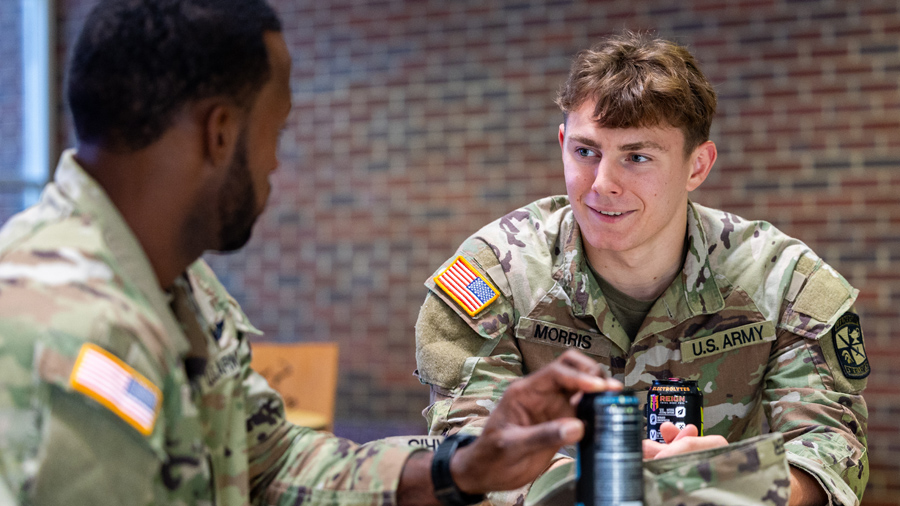 Military students in uniform sitting at a table talking.