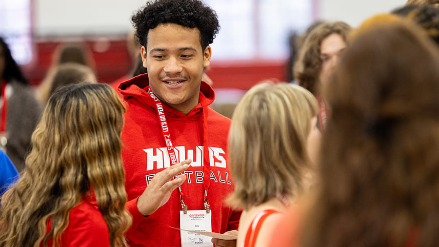 New student wearing a Hawks football (local high school) hoodie and talking to other new students during orientation.