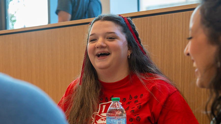 A small group of students laughing amid their conversation.