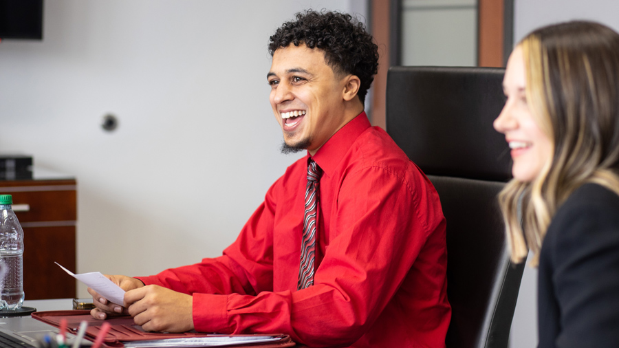 Student smiling/laughing while sitting at a conference table 