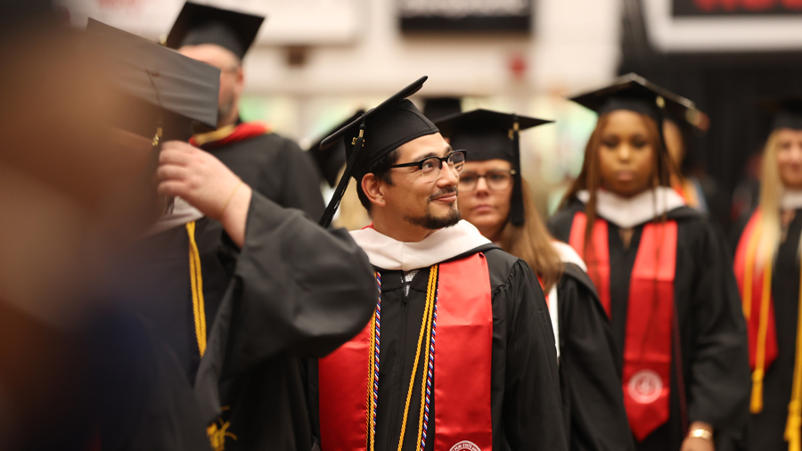 Student looking into the crowd as they walk in commencement