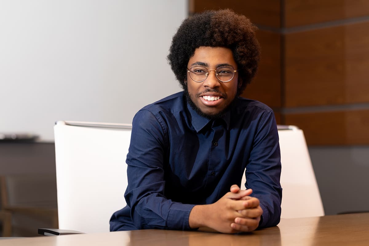 Kameron, in mid-conversation, sitting at a conference table in an office