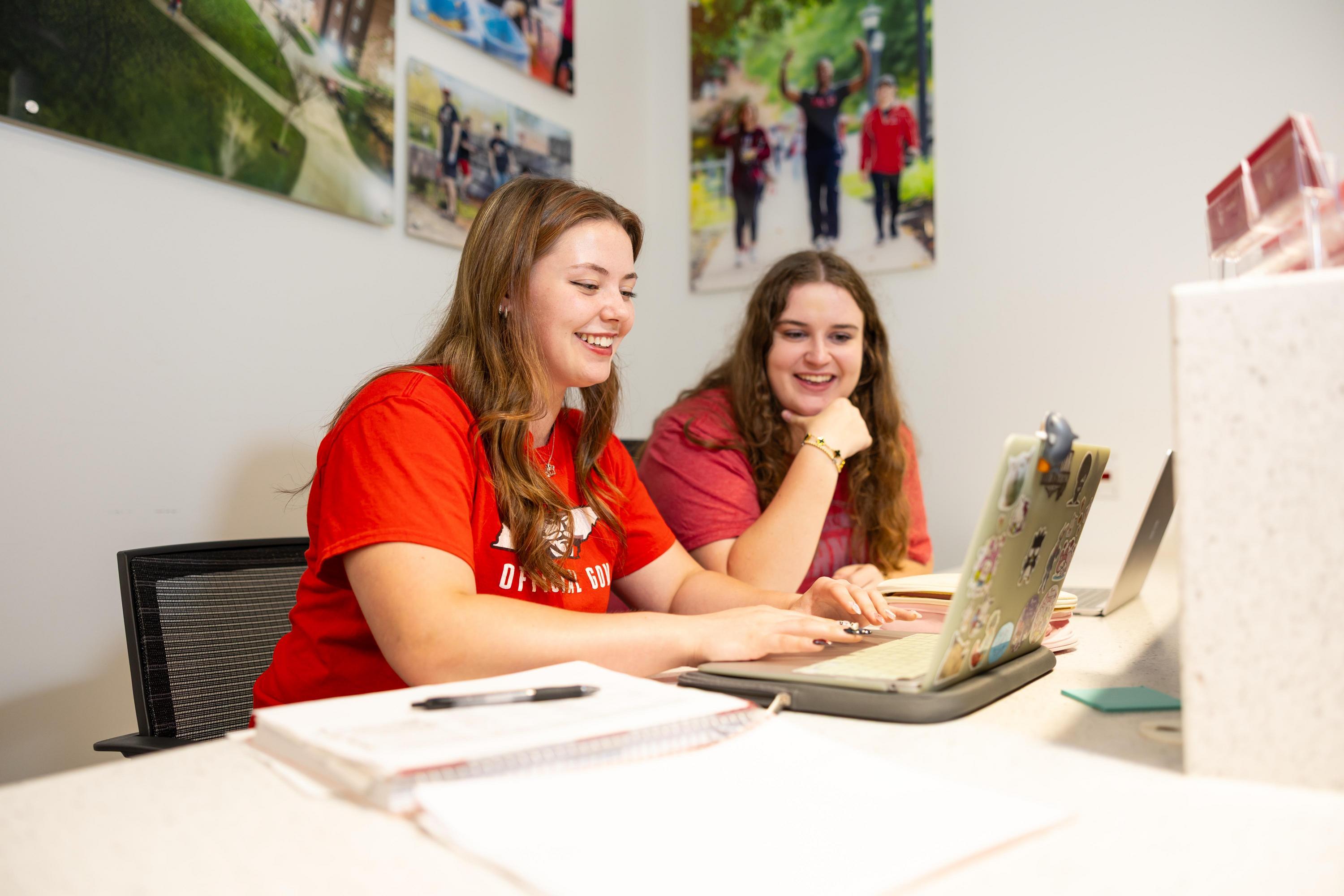 students smiling at laptop
