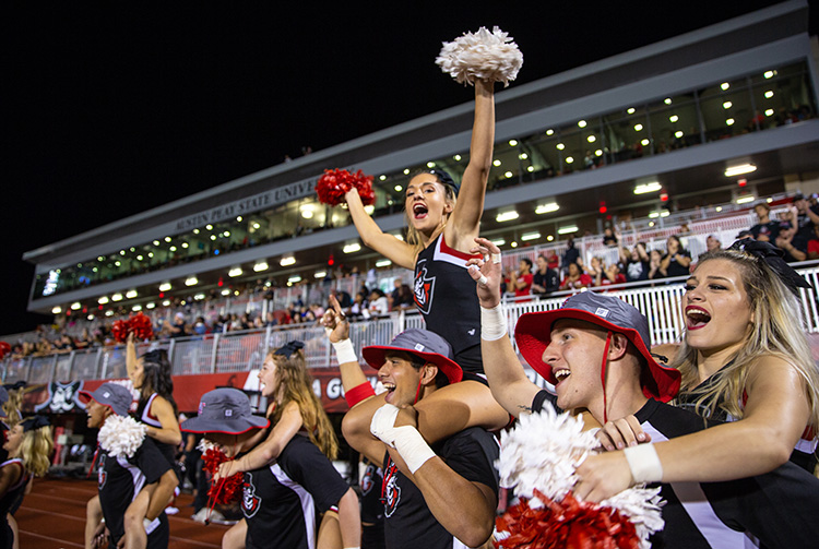 Cheerleaders cheer on sidelines at football game