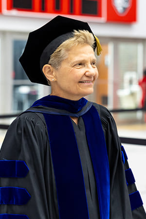 Dr. Ann Silverberg walking down the aisle in her regalia during a commencement ceremony.