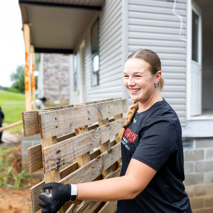 Student carrying a pallet to help clean up.