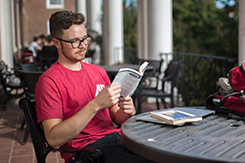 Student reads book on Harned balcony