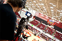 Student operates camera at basketball game