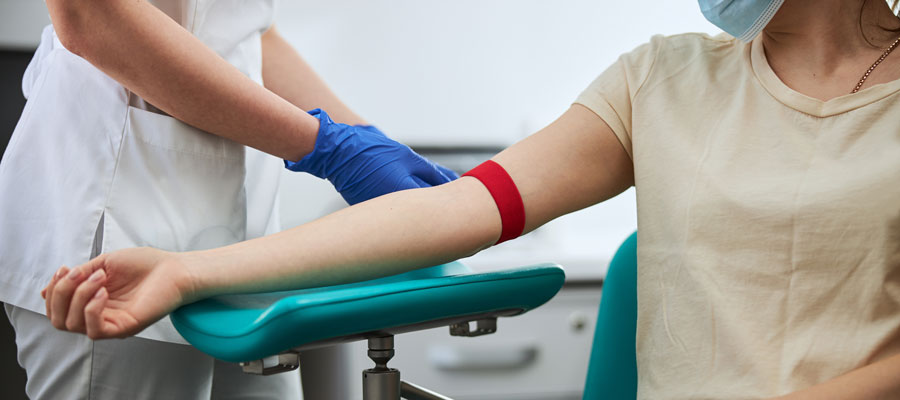 Patient holding out their arm while a Phlembotomist gets ready to draw their blood.