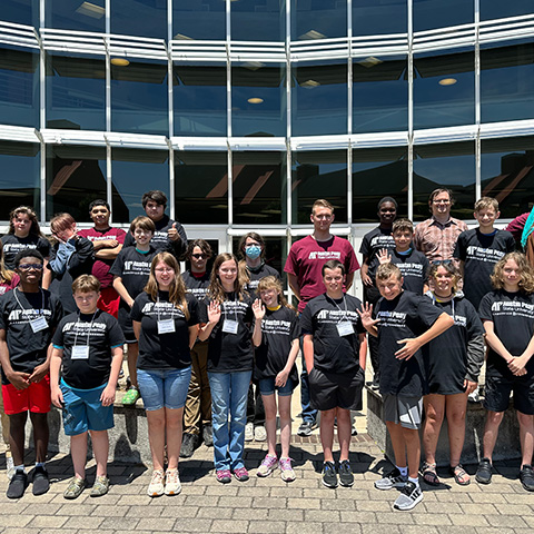 Group of campers posing for a picture infront of the Mathematics building.