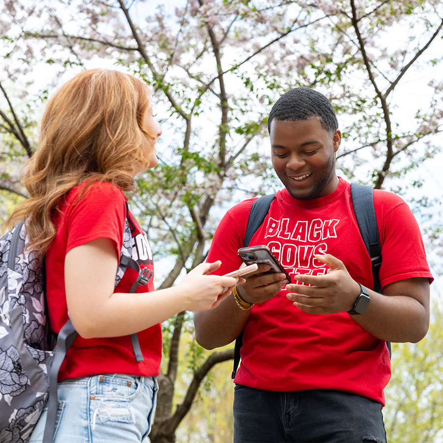 Students talking outside while looking at their phones