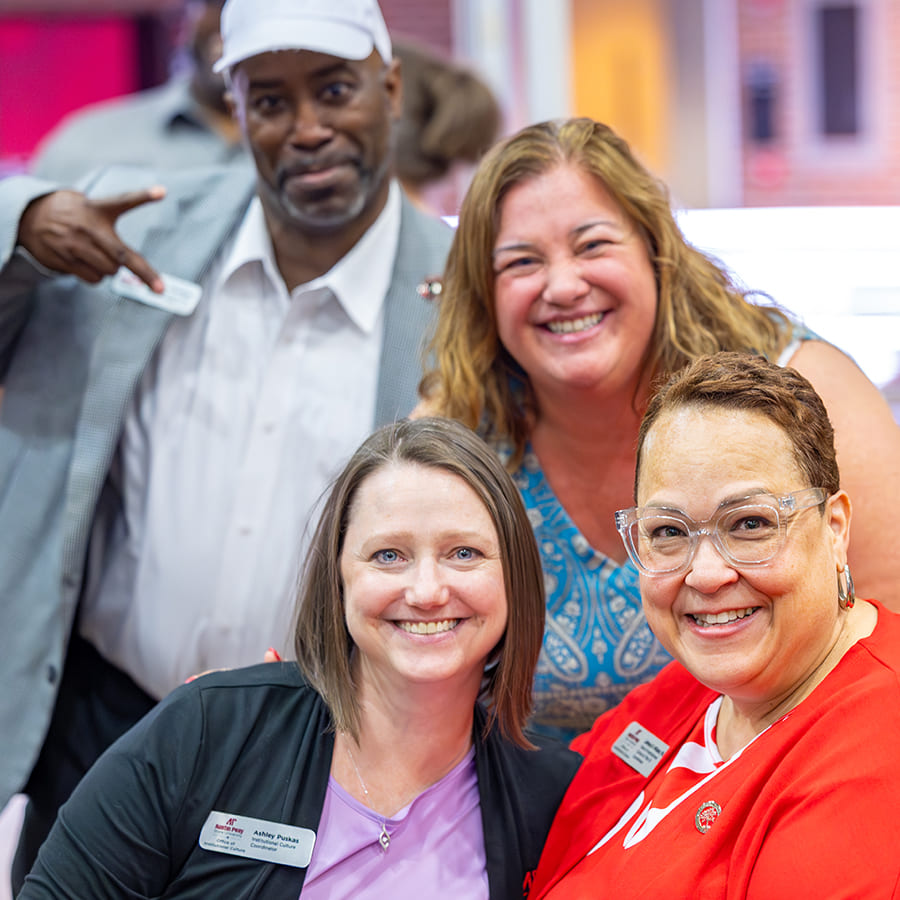 Four smiling staff members posing together at an awards event.