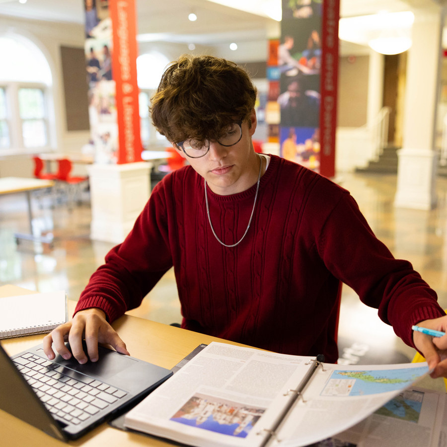 Student working on his classwork in the Harned Lobby
