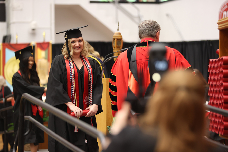Jennifer Stevens walking across the the stage to receive her degree at graduation