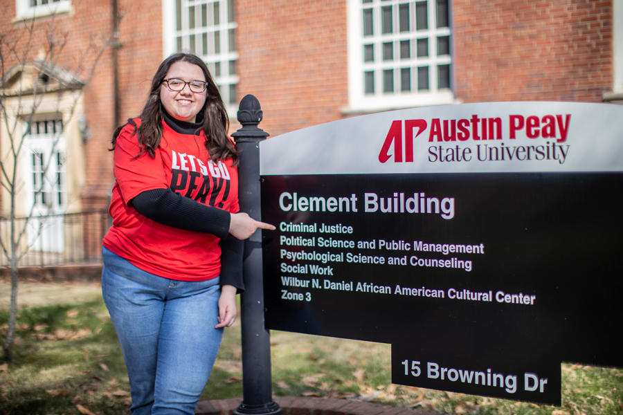 Skylar Smith pointing to Criminal Justice on the Clement Building Sign