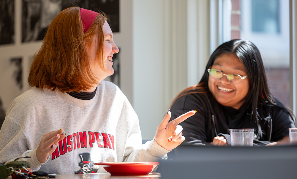 Two students talking and laughing in the food hall.