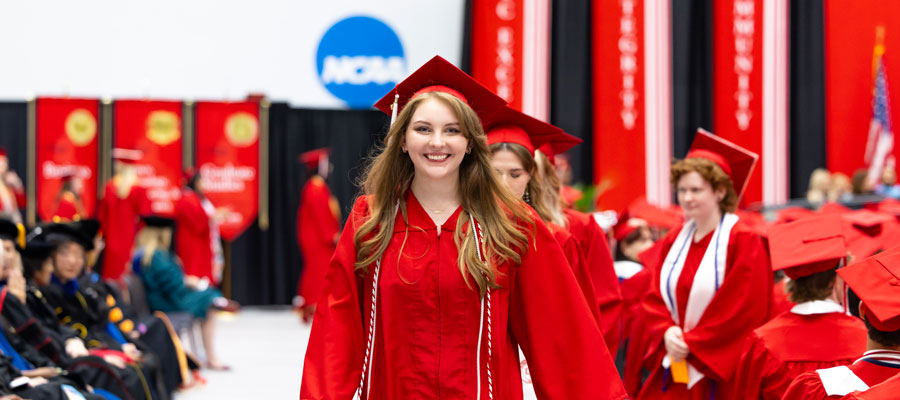 Student walking toward the stage to recieve their diploma at commencement.