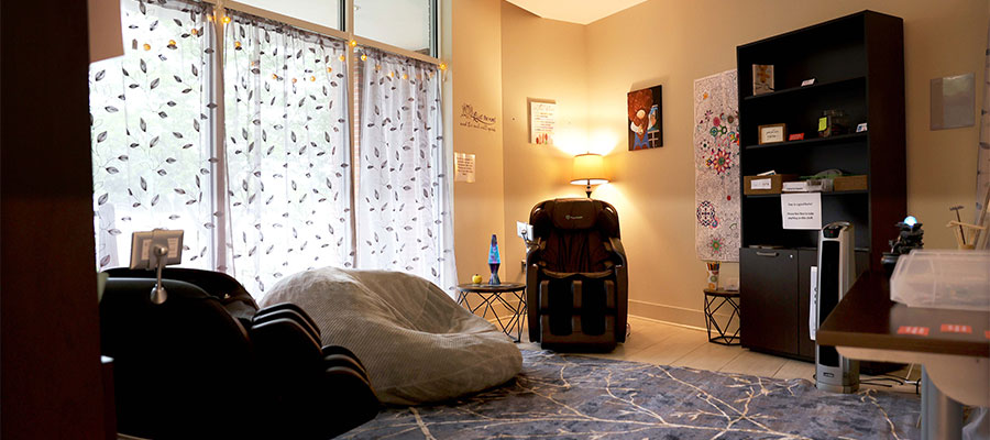 Inside of the Zen Den showing soft lighting with two massage chairs and a giant bean bag.