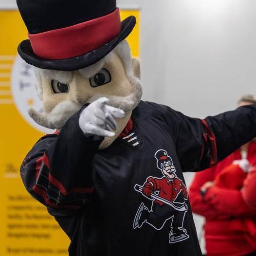 The Governor mascot wearing a hockey jersey and pointing at the camera.
