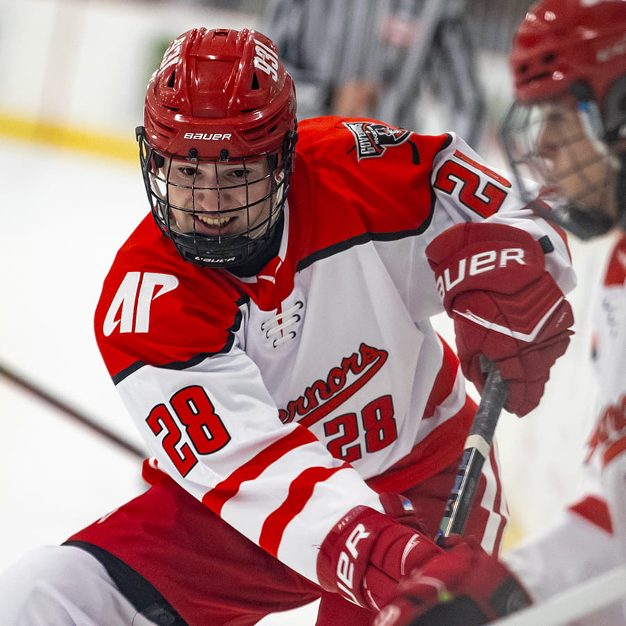 Ice hockey player in a red and white jersey with number 28 reaching with a stick