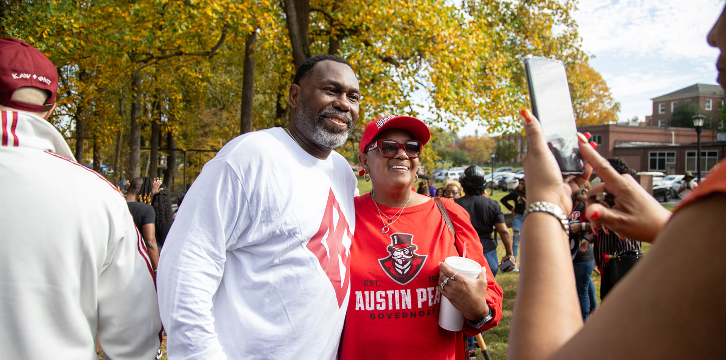 Two people posing for a picture at the Homecoming Tailgate party. 