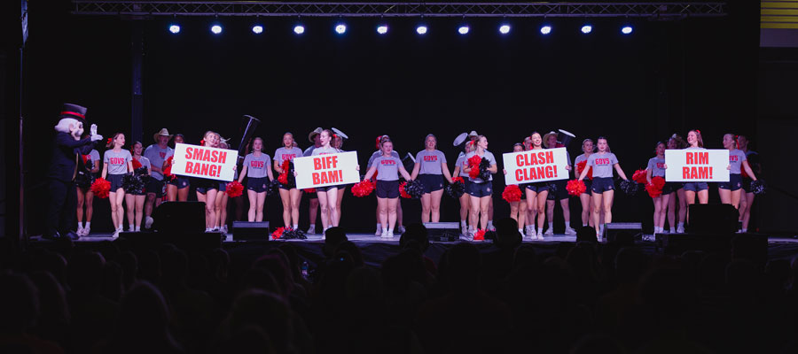 Chearleaders on stage holding up lyrics to the fight song.