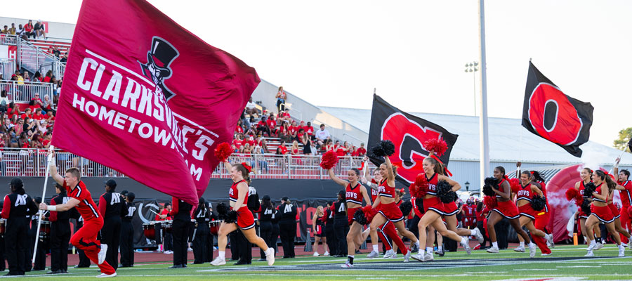 Cheerleaders running onto the field before the game carrying flags that spell out GOVS