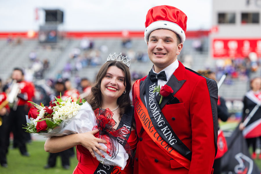Homecoming King and Queen posing for a picture at the football game.