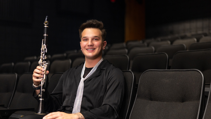 Smiling young man holding a clarinet in an empty theater