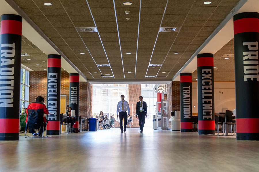 Students walking among the Pillars in the Morgan University Center that say Pride, Tradition, and Excellence.
