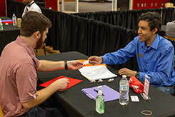 Two business people exchange a business card at a table during a career fair.