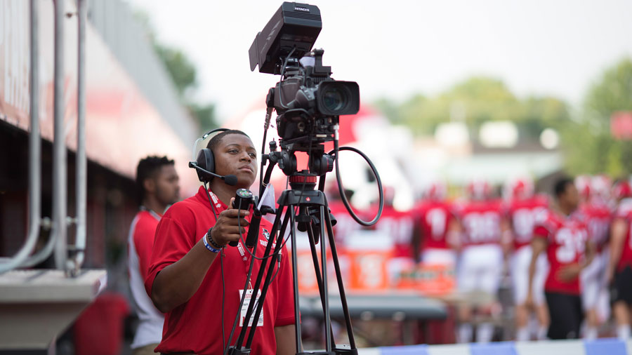 Student operating a camera at a home football game.