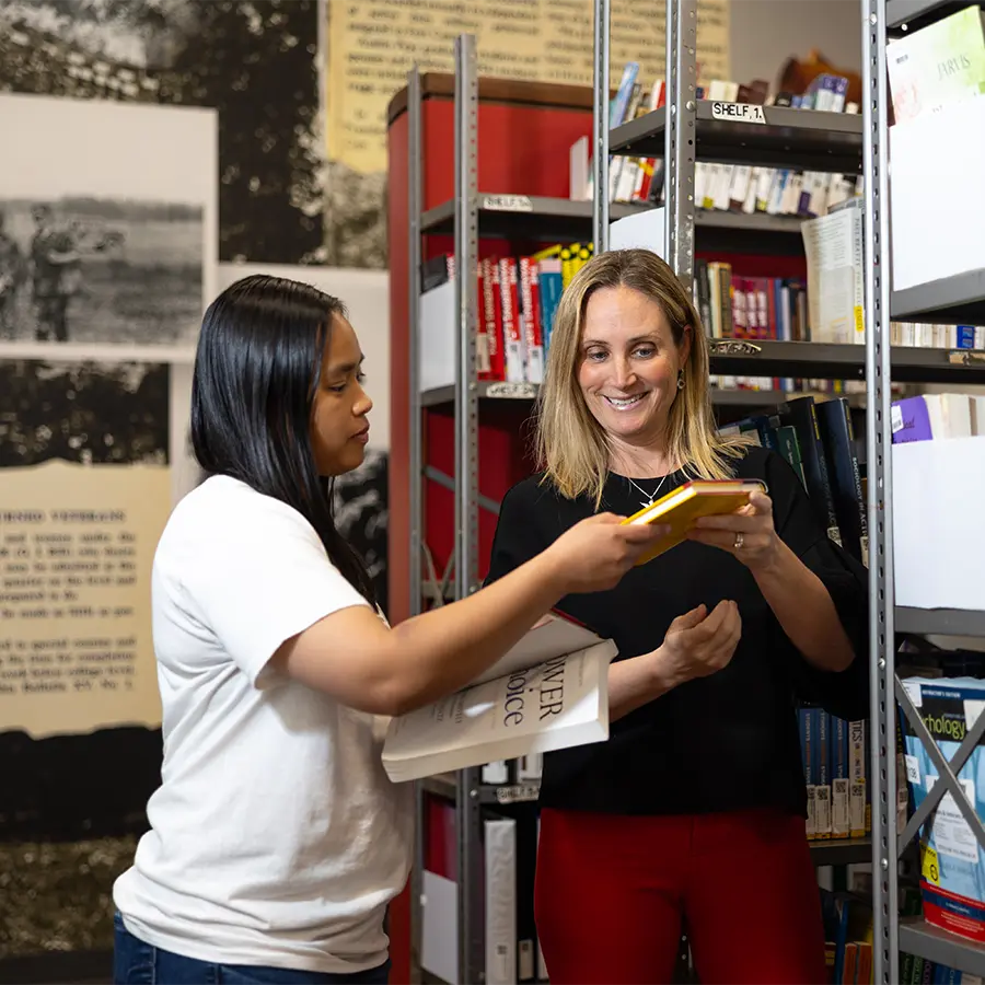 Student being handed a textbook from a shelf.